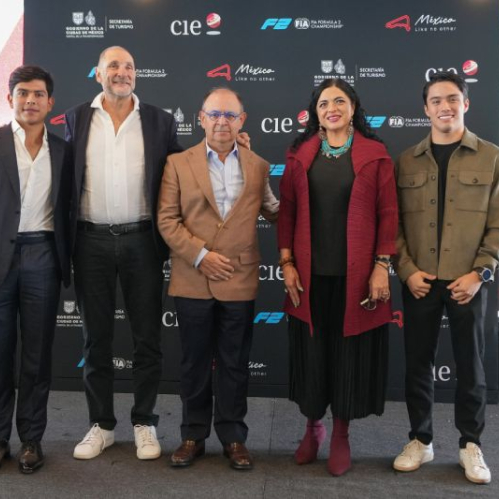 Fotografía de la conferencia de prensa con directivos y los pilotos mexicanos Rafael Villagómez y Noel León posando sonrientes sobre un escenario con el mampara promocional del evento.