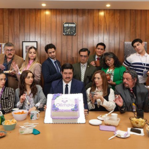 Un grupo de empleados celebra alrededor de una mesa en una oficina, con pastel, comida y ambiente festivo, evocando el tono humorístico y cotidiano de la serie.