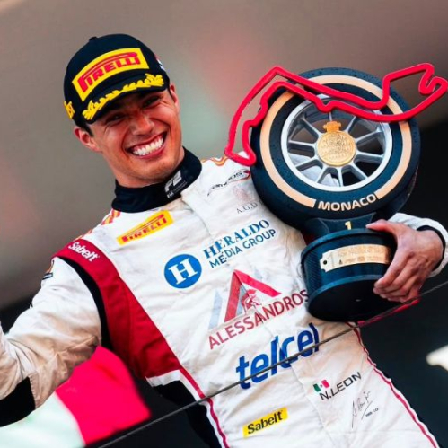 Piloto de automovilismo celebra en un podio sosteniendo un trofeo con el trazado de Mónaco.