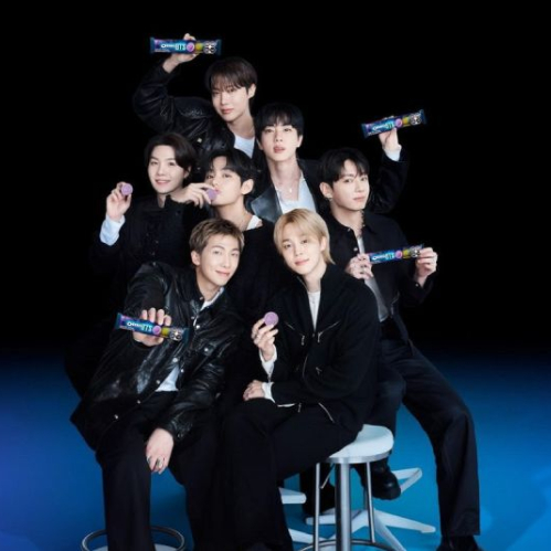 Fotografía promocional de los siete integrantes de BTS (RM, Jin, SUGA, j-hope, Jimin, V y Jungkook) vestidos con atuendos negros, posando juntos en un estudio con paquetes y galletas moradas de la edición limitada de OREO x BTS.