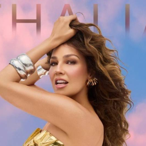 Mujer posando frente a un cielo en tonos pastel, con joyería metálica y estilismo glamoroso que resalta su presencia escénica.