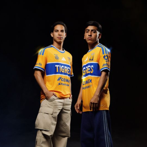 Fotografía promocional del jersey de local de Tigres 2026–2027 con dos personas portando la indumentaria auriazul.
