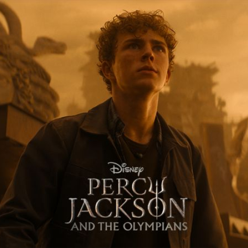 Fotografía promocional de la serie de Disney+ "Percy Jackson y los dioses del Olimpo". Walker Scobell interpreta a Percy Jackson en un plano medio, mirando hacia arriba con expresión seria contra un fondo cálido en tonos dorados que muestra una estatua clásica de Medusa y estructuras antiguas. En el centro inferior se muestra el logotipo oficial en inglés de la serie.