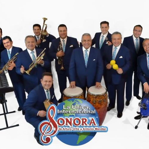 Fotografía promocional de una agrupación musical tropical con instrumentos y vestimenta formal.