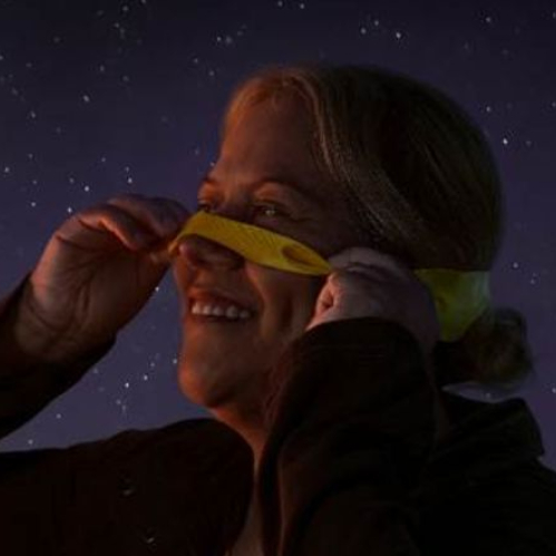 Persona al aire libre retirando una venda amarilla bajo un cielo nocturno estrellado, acompañada de un mensaje institucional de Fundación Cinépolis.