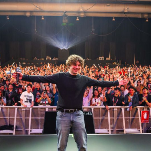 Un creador en escenario frente a una multitud entusiasta durante un evento de cultura pop.