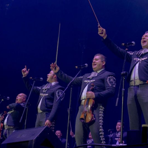 Grupo de mariachis interpretando música en escenario iluminado.