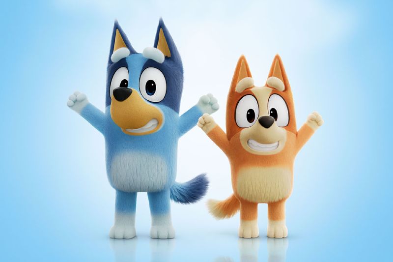 Primer vistazo a Bluey La Película Ilustración en 3D/CGI de los personajes Bluey y Bingo celebrando con los brazos en alto sobre un fondo azul claro con nubes suaves.
