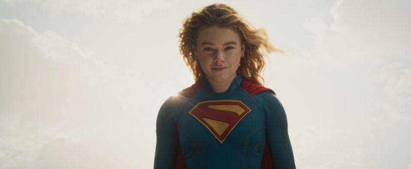 Supergirl – Arte promocional Figura con traje de superheroína posando frente a un cielo iluminado por luz solar.