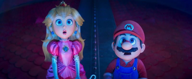 Super Mario Galaxy: La Película — Primer vistazo Mario y Peach observan sorprendidos algo fuera de cuadro en un entorno oscuro con piso de baldosas rojas y una estructura metálica al fondo.