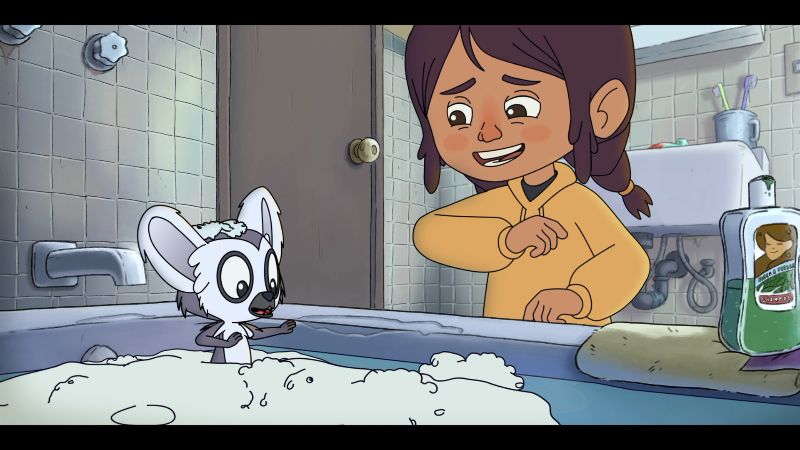 Niño inclinado sobre una bañera llena de espuma donde un pequeño lémur aparece sorprendido.