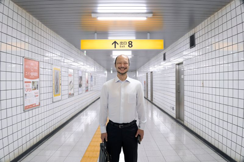 Persona de traje bajo un letrero amarillo que indica “Exit 8”.