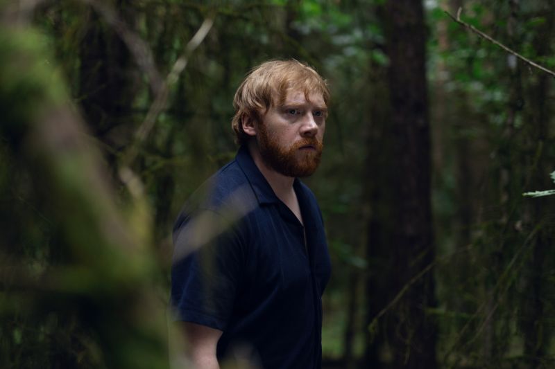 Engendro — Jon en el bosque Persona en un bosque denso rodeado de árboles y luz filtrada.