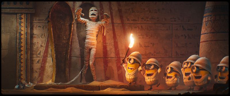 Minions exploradores dentro de una tumba egipcia frente a una momia emergente.