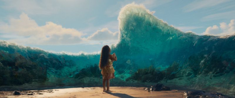Moana — Encuentro con el océano Moana observa una ola monumental que se eleva frente a ella en una playa tropical.