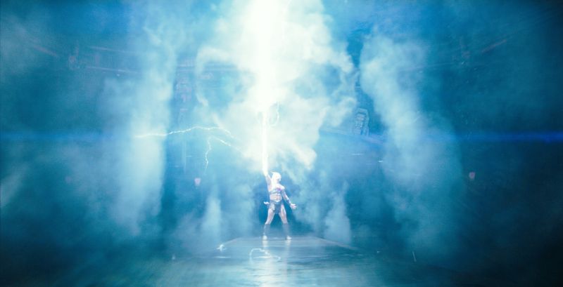 Amos del Universo — Poder desatado Figura recibiendo rayo de energía en escenario lleno de humo.