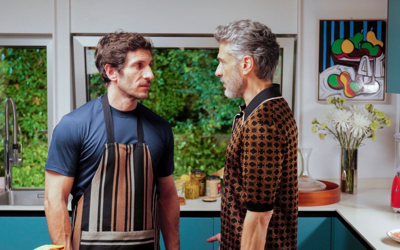 Dos personas conversando en una cocina moderna iluminada.