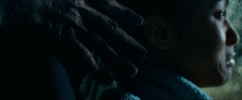 El Pasajero del Diablo — Aparición demoniaca Mano espectral iluminada tratando de alcanzar a una mujer aterrada dentro de un vehículo bajo atmósfera de suspenso.