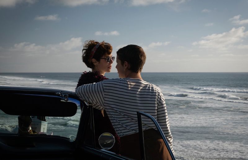Frente al mar — La vida es Dos personas conversando junto a un auto frente al océano.