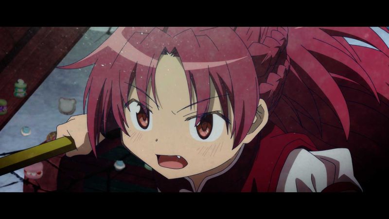 Kyoko Sakura con su atuendo rojo sosteniendo su lanza con una expresión decidida y combativa.