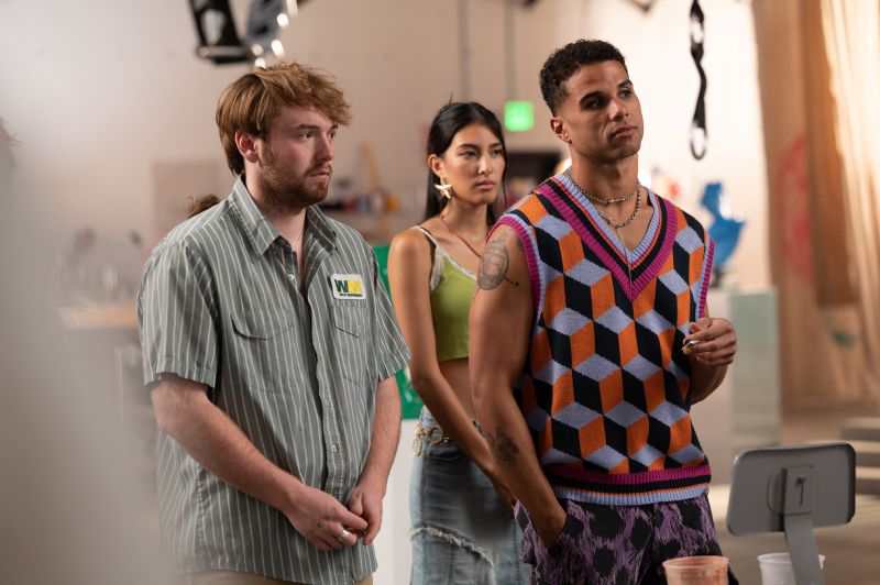 Entorno Artístico de la Película Cooper Hoffman con camisa a rayas junto a otros dos actores en un estudio o taller artístico.