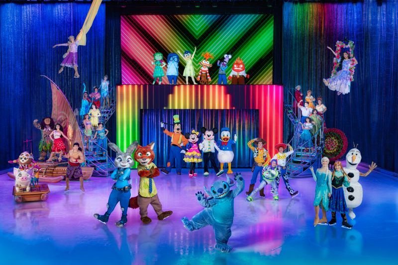 Disney On Ice — Escenario principal Elenco completo de personajes de Disney reunido en un escenario multicolor sobre hielo durante una rutina grupal.