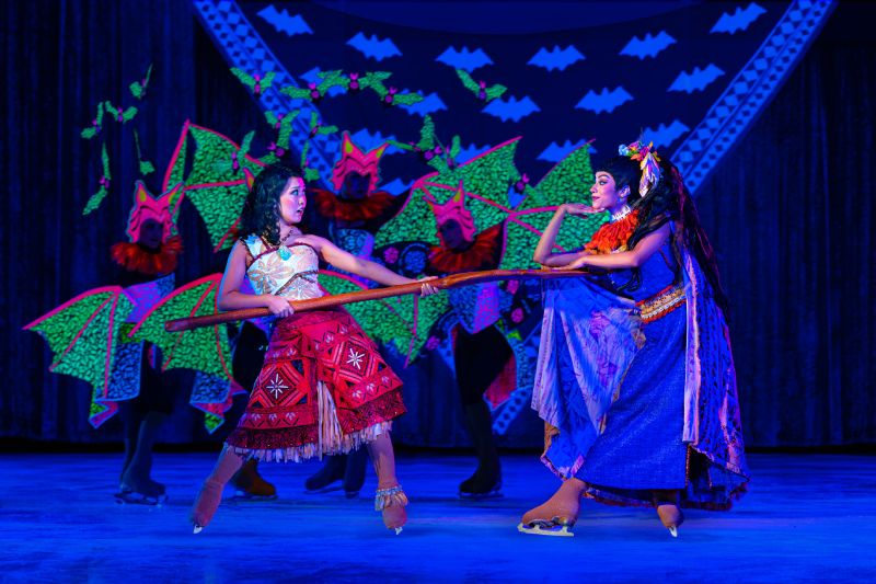 Disney On Ice — Confrontación polinesia Dos intérpretes enfrentados en una coreografía inspirada en la mitología polinesia, rodeados por bailarines con alas verdes.