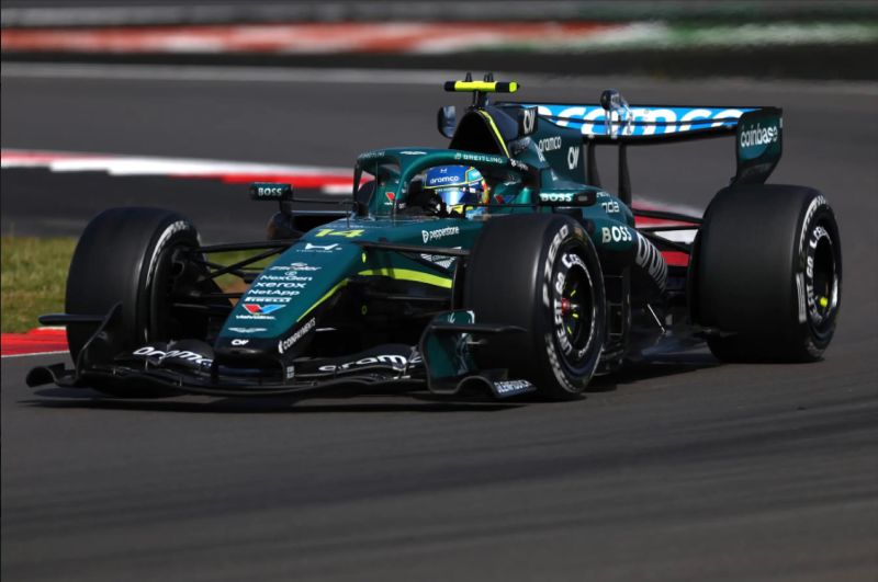 Aston Martin en acción durante el GP de Gran Bretaña Monoplaza de competición en pista durante una curva, con diseño y colores característicos de un equipo de Fórmula 1.