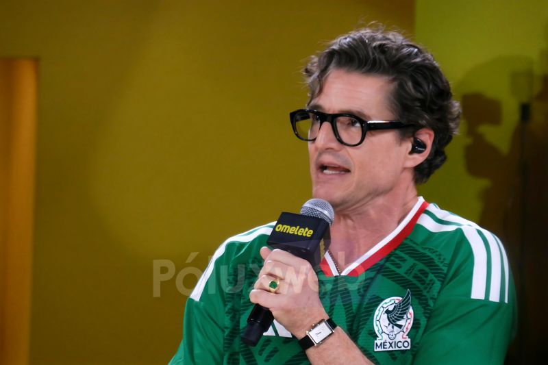CCXPMX26 – Día 3: Pedro Pascal en el Omelete Stage Persona con playera de la Selección Mexicana sosteniendo un micrófono con el logo de Omelete, sobre un fondo amarillo, en un ambiente de entrevista o panel.