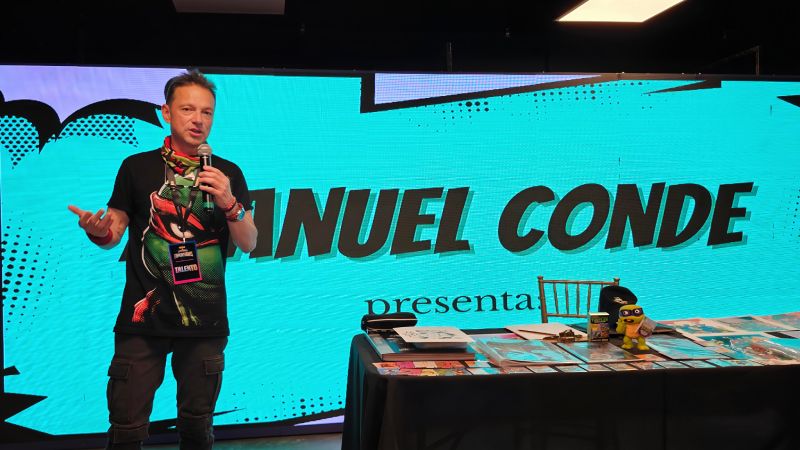 Taller de Ilustración con Manuel Conde El ilustrador Manuel Conde impartiendo un taller de dibujo sobre las Tortugas Ninja frente a una pantalla gigante interactiva con su nombre.