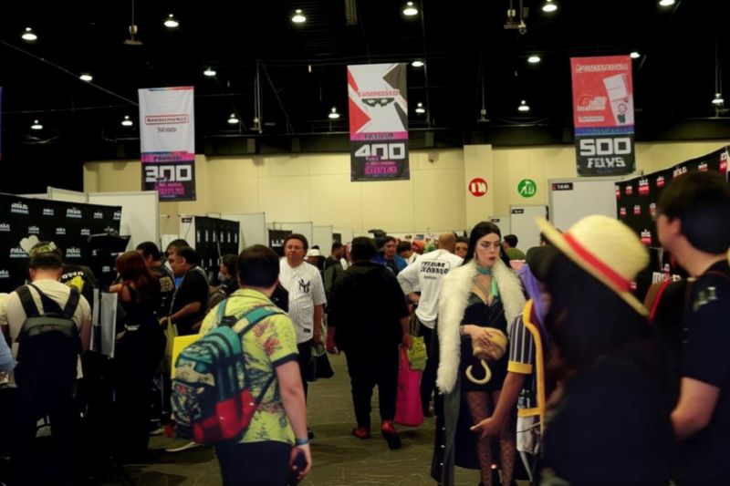Piso de exhibición de AniMole 4 Vista general del piso de exhibición de AniMole 4 en el WTC de la Ciudad de México, mostrando pasillos amplios transitados por asistentes y cosplayers, bajo banners publicitarios con números de pasillos colgando del techo.