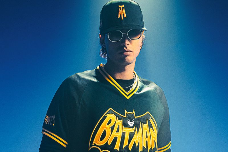 Jersey de la colaboración New Era x Batman x Sultanes Persona con jersey y gorra inspirados en Batman, iluminado con tonos azules en un entorno oscuro.