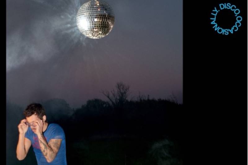 Arte promocional de Kiss All The Time. Disco, Occasionally. Figura en un entorno nocturno con una esfera disco suspendida sobre su cabeza, iluminando el paisaje con reflejos brillantes.