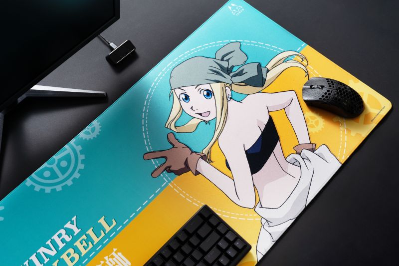 Arbiter Studio x Fullmetal Alchemist Brotherhood Escritorio con alfombrilla temática de anime, teclado y mouse sobre una superficie ilustrada con un personaje rubio y elementos mecánicos.