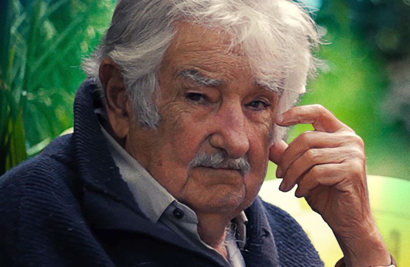 “Pepe Mujica: Un pasajero infinito” – Arte promocional Retrato de un hombre mayor sentado al aire libre, con expresión serena y vegetación de fondo, acompañado del título del documental.