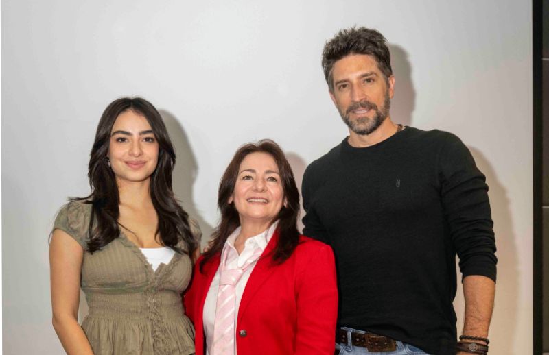 Fotografía de tres personas posando frente a un fondo claro en un entorno de presentación o anuncio.