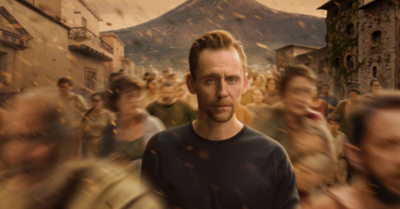 Pompeya Más Allá del Tiempo Póster promocional con Tom Hiddleston frente a una representación de Pompeya durante la erupción del Vesubio.