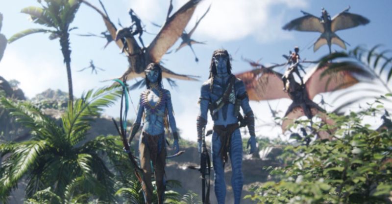 Dos figuras humanoides de piel azul se encuentran en un entorno selvático mientras criaturas aladas sobrevuelan el paisaje.