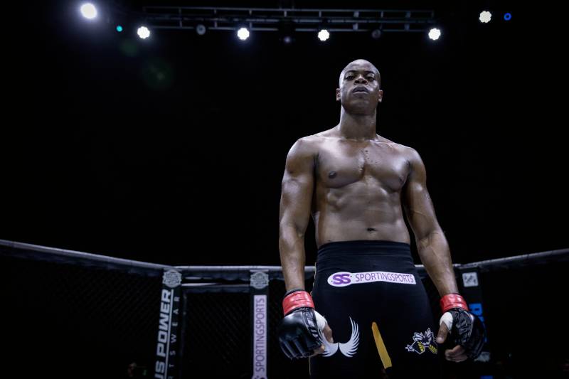 Peleador de MMA en el octágono Imagen de un atleta de artes marciales mixtas dentro de un octágono, preparado para un combate, con iluminación de escenario y ambiente competitivo.