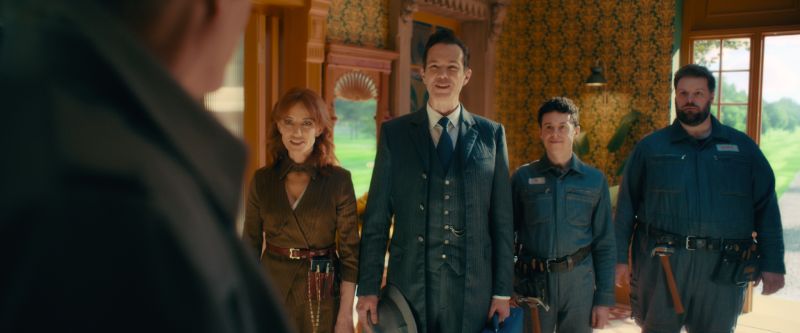 Representación Humana de las Inteligencias Artificiales Grupo de personajes representando a las inteligencias artificiales JARVIS, FRIDAY y E.D.I.T.H. en trajes elegantes dentro de una casa.