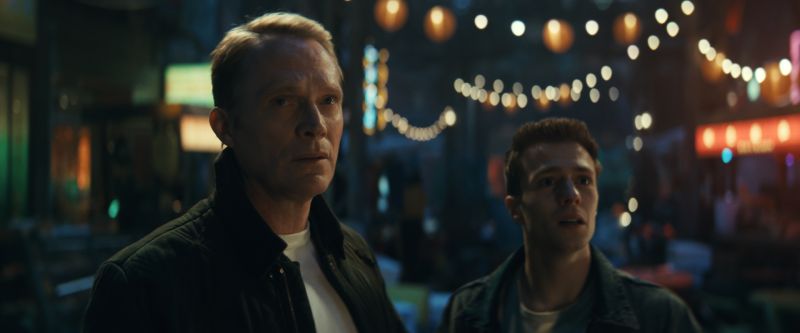 Visión y Tommy Shepard Paul Bettany junto a Ruaridh Mollica como Tommy Shepard observando sorprendidos en una calle iluminada por luces nocturnas.