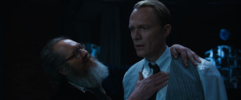 James Spader y Paul Bettany en VisionQuest James Spader en su avatar humano con barba gris y anteojos colocando una mano sobre el pecho de Paul Bettany.