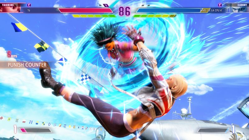 Captura de pantalla de combate aéreo en la que Yasmine conecta un Punish Counter en pleno aire sobre Cammy sobre un escenario con barcos y cazas militares.