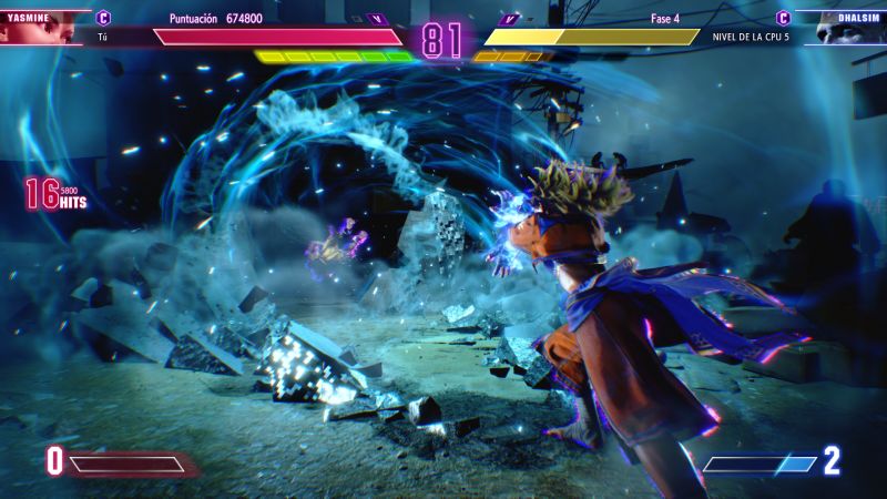 Captura de pantalla de combate mostrando el clímax visual de un Super Art de Yasmine con destellos de energía azul, polvo y escombros proyectados mientras ataca a Dhalsim.