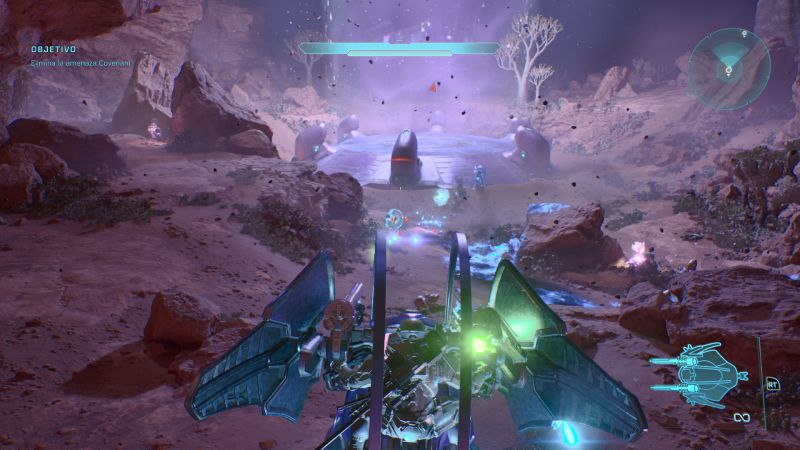 Combate aéreo a bordo del Banshee en Halo: Campaign Evolved Vista posterior de un Banshee aliando volando sobre un cañón desértico con una estructura alienígena al fondo bajo un cielo nocturno iluminado.