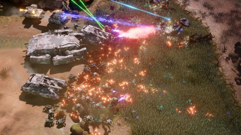 Enfrentamiento masivo entre tanques y alienígenas Vista superior de una intensa batalla RTS donde tanques futuristas disparan láseres azules y rosas contra una horda de criaturas alienígenas en un bioma selvático.