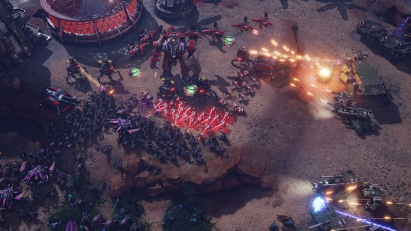 Combate entre mechas gigantes y hordas enemigas Enfrentamiento multitudinario que muestra a un mecha gigante rojo disparando misiles sobre una horda de criaturas alienígenas moradas que asaltan la base.