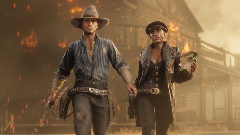 Red Dead Online – Actualización mensual Dos personajes armados frente a una estructura en llamas en un entorno del Viejo Oeste.