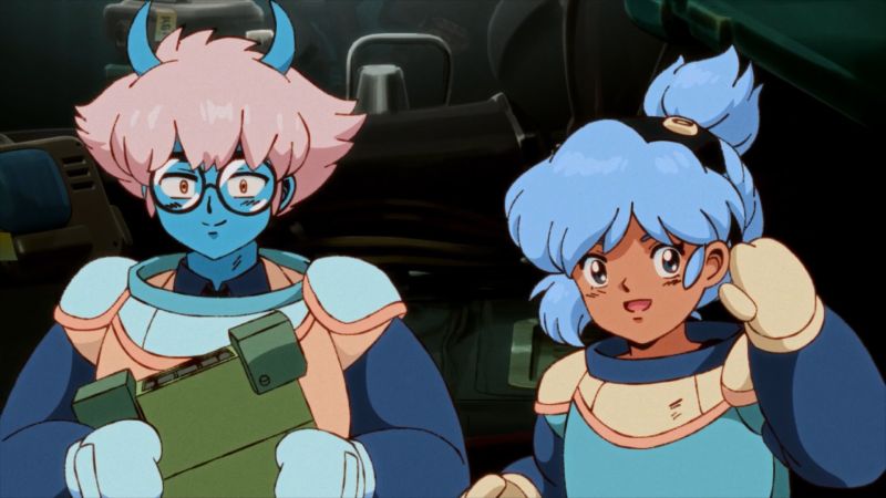 Dos personajes animados con trajes futuristas conversan en un entorno tecnológico.