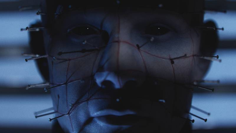Rostro marcado por hilos y agujas Primer plano de un rostro intervenido con múltiples agujas conectadas por hilos tensos, iluminado por una luz tenue que resalta las sombras y acentúa la atmósfera inquietante.